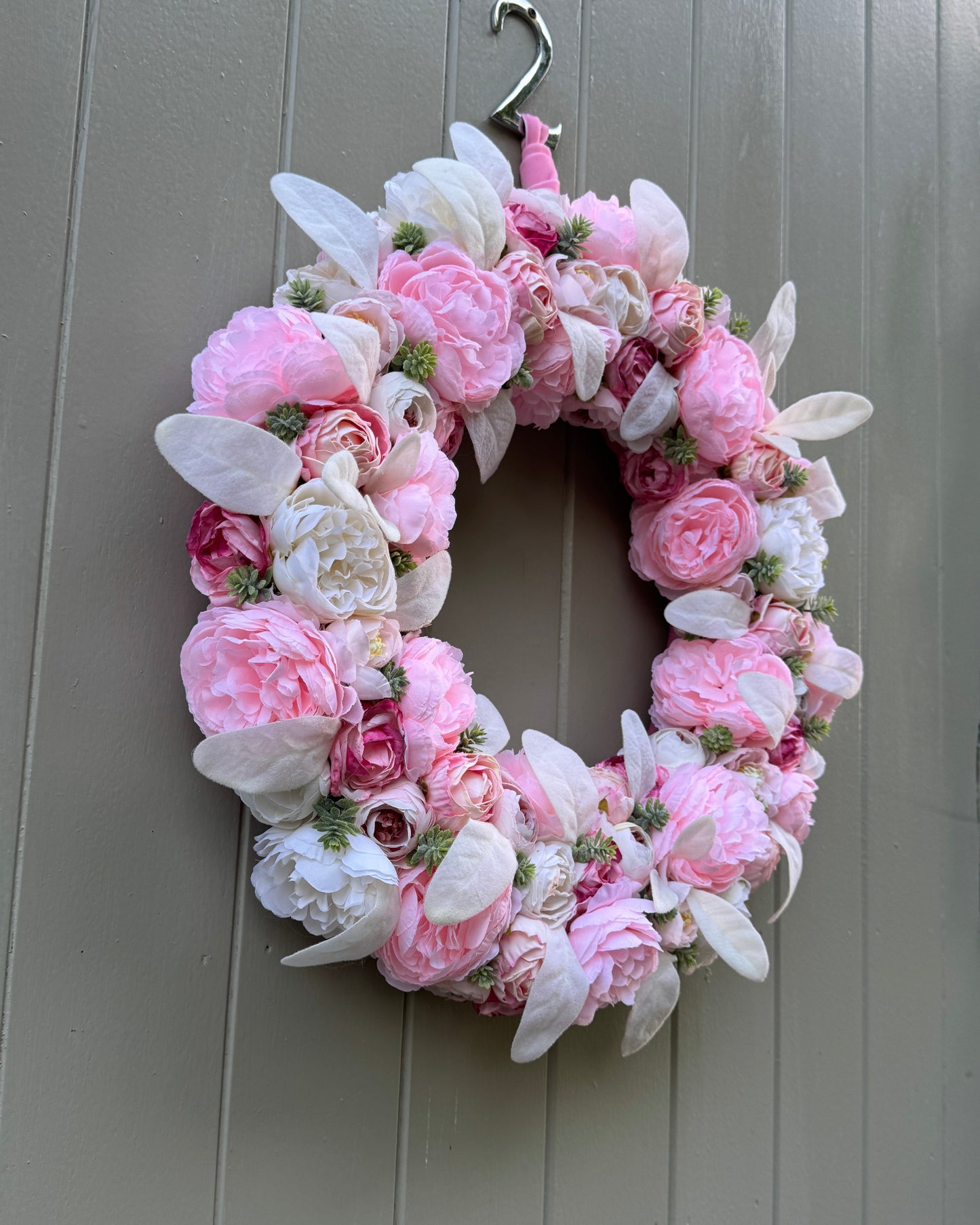 A floral wreath made of artificial flowers in different shades of pink