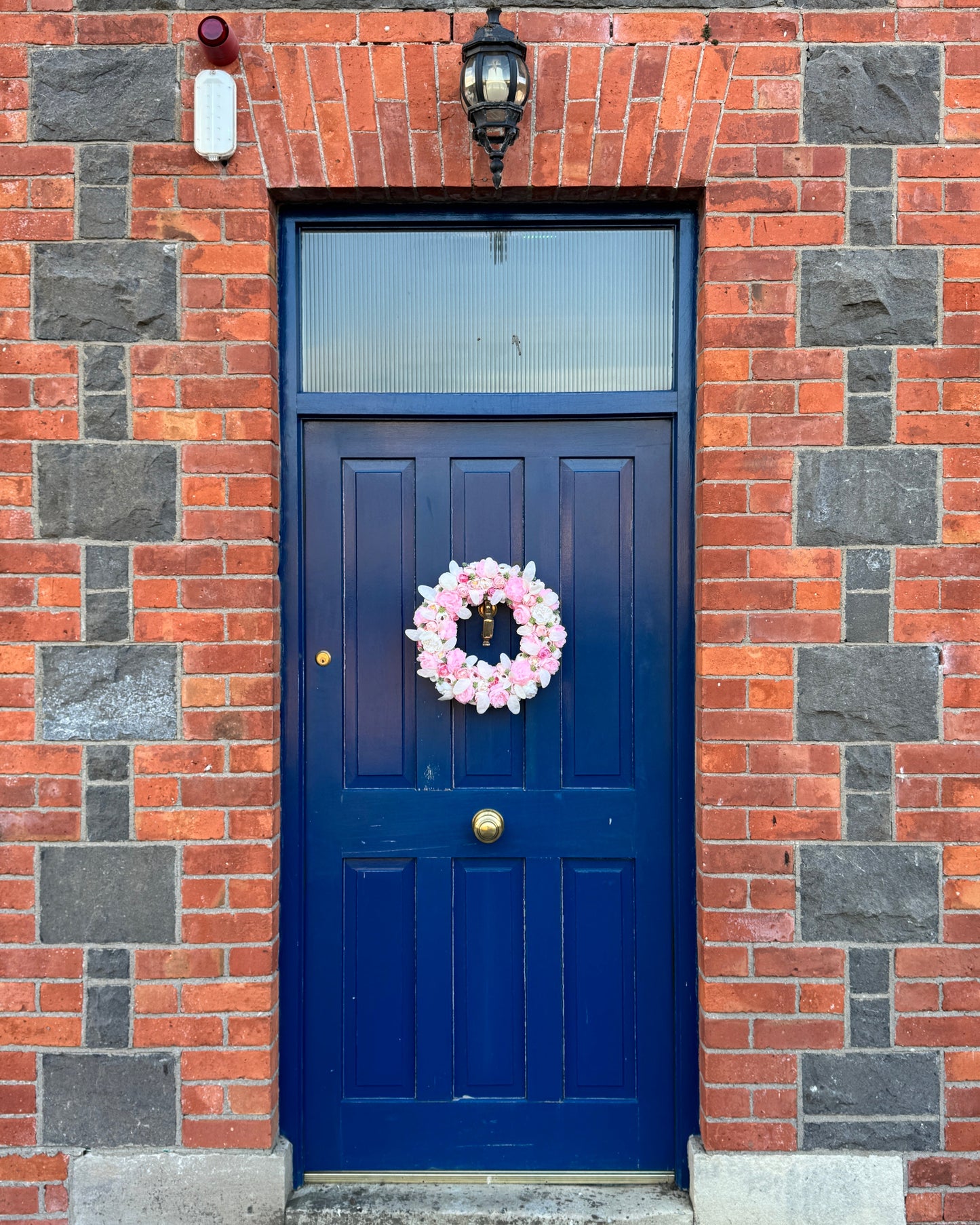 A white and pink floral wreath decorating a blue door