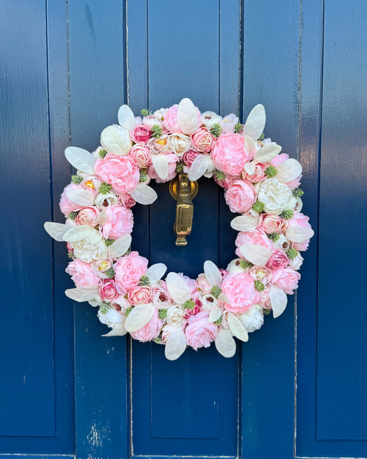Beautiful floral wreath of white and pink artificial flowers with addition of white foliage
