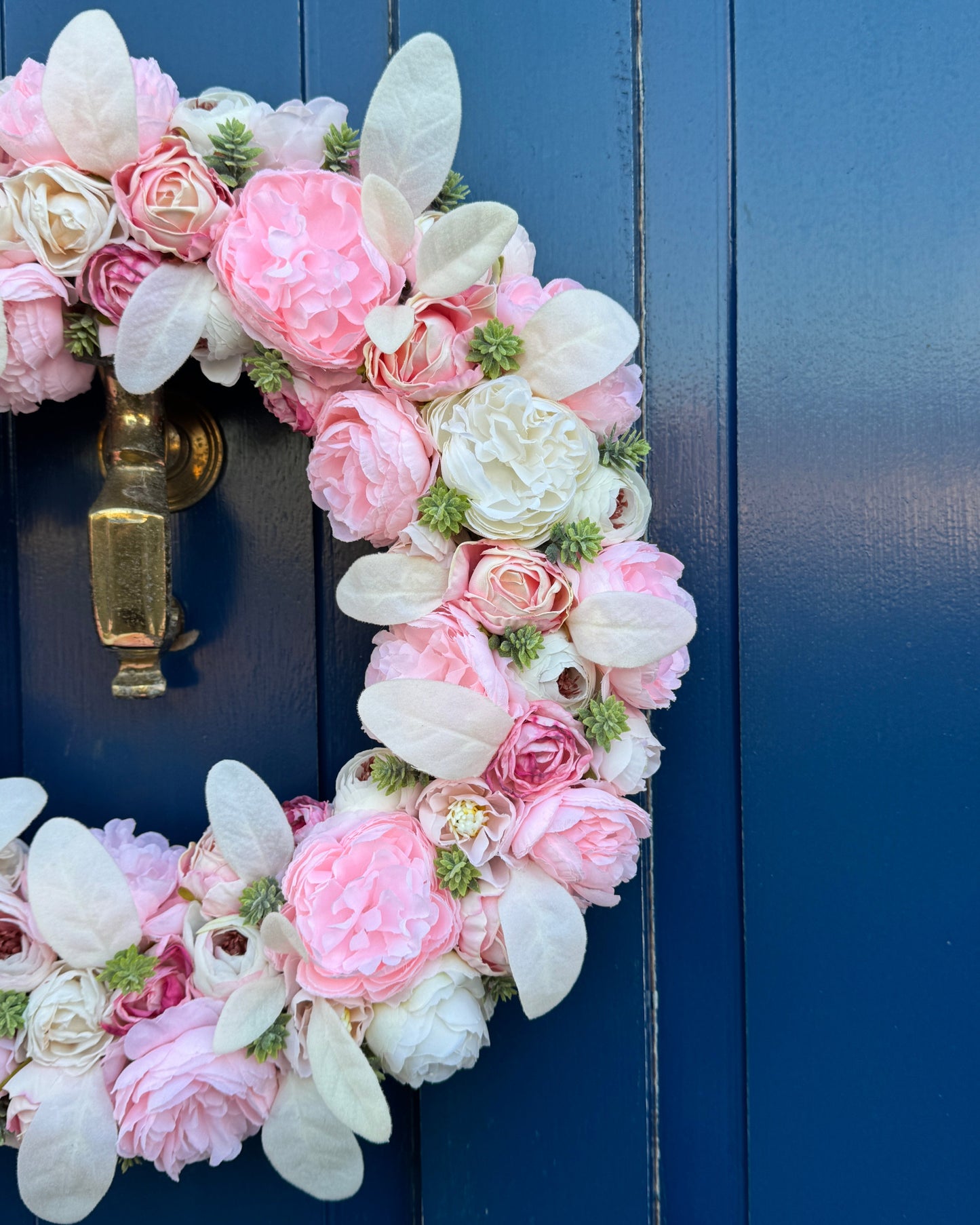 Half of an artificial floral wreath made with white and pink peonies and roses