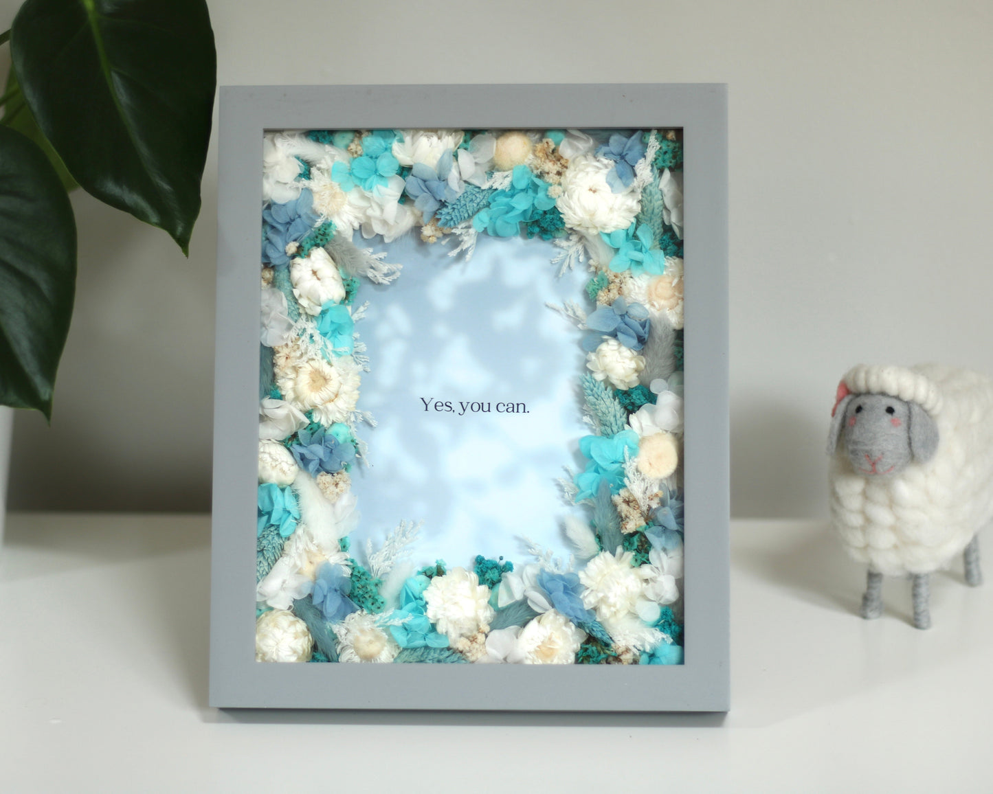 Grey photo frame with decorative blue and white flowers and a cute sheep on the left
