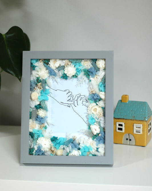 Highland Waters floral frame near a decorative house figurine