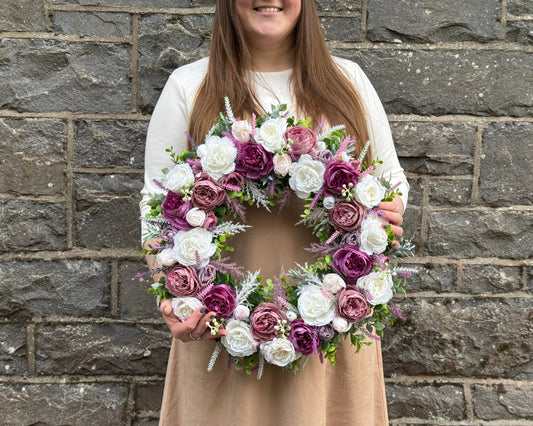 Girl holding a floral wreath of mauve and ivory peonies
