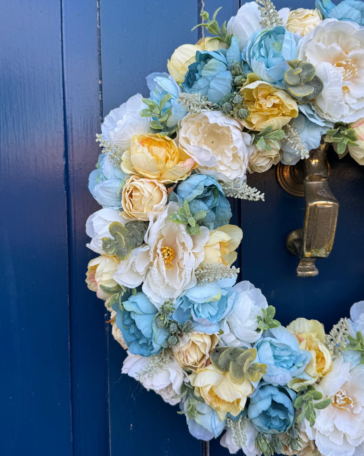 Half of a decorative floral wreath with artificial flowers of yellow and blue colours