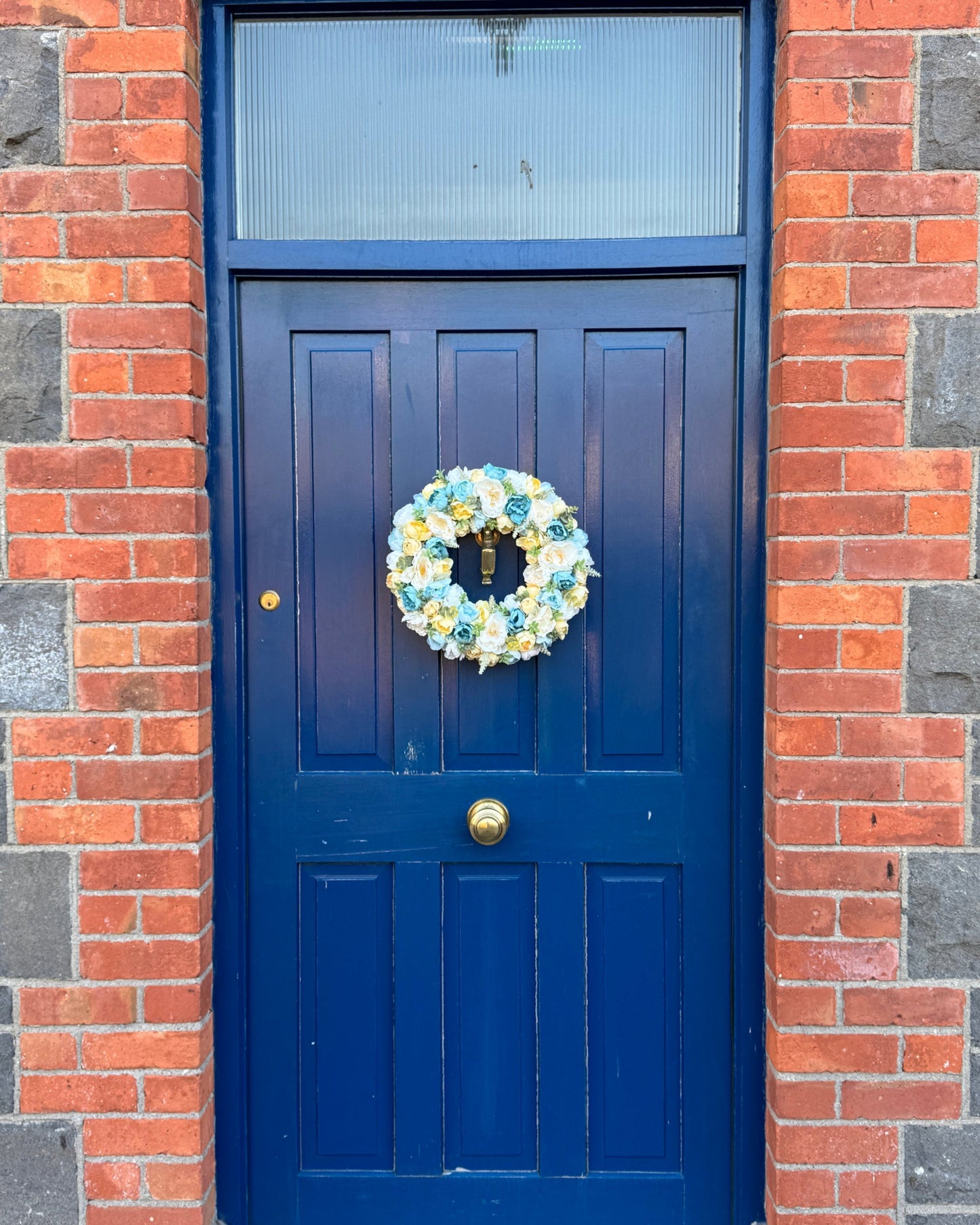 A yellow and blue floral wreath decorates a blue door
