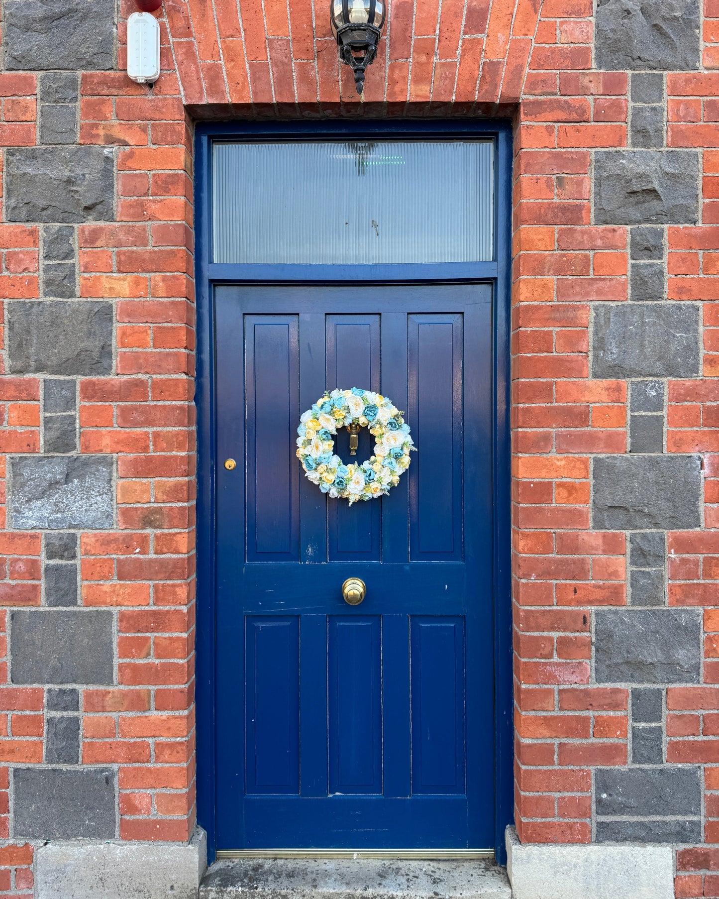 A floral wreath made from blue and yellow decorates a blue door