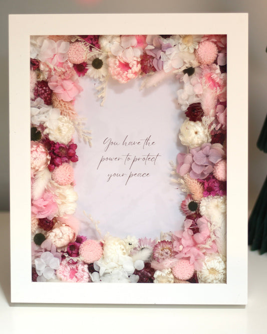 A beautiful white decorative frame for photos with pink flowers and a motivational phrase