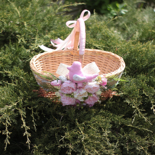 An Easter basket with white and rose flowers and a toy bird