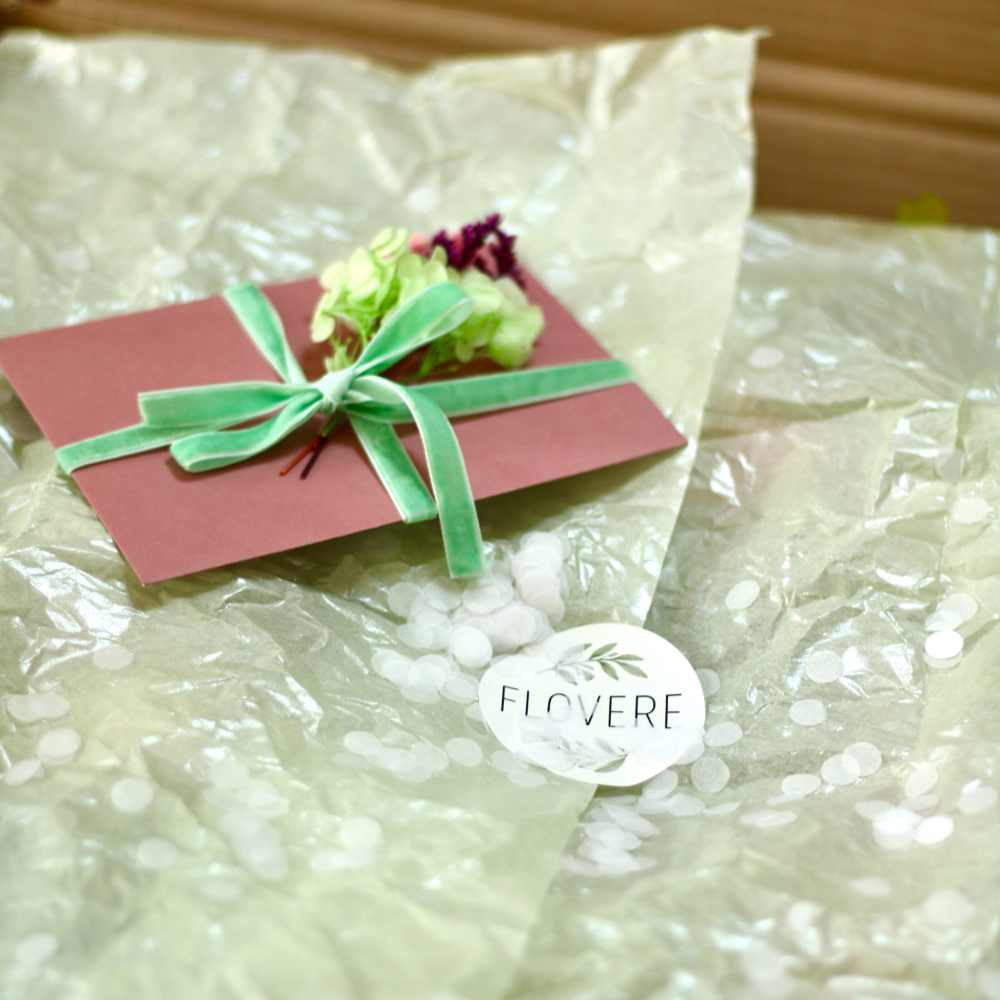 Packaging paper covering a flower wreath with a wrapped card on top