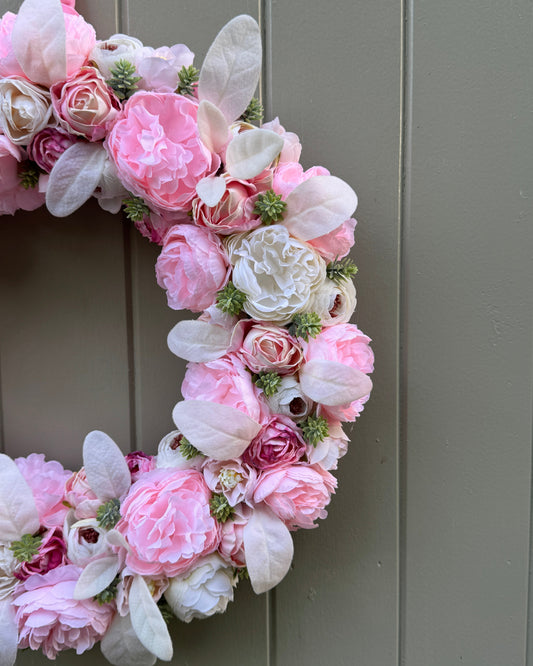 Half of a white-pink floral wreath with cream foliage