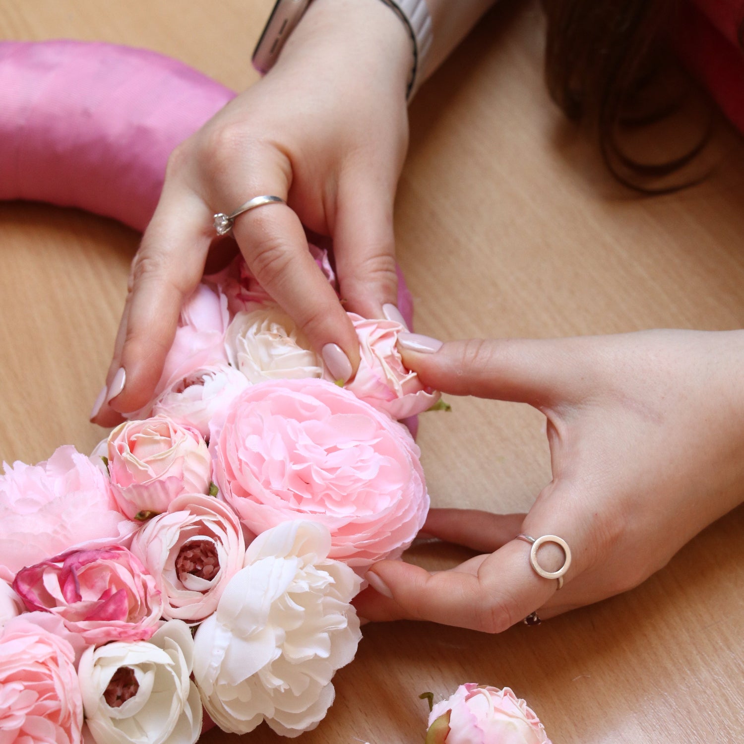 A woman fixes an artificial flower on a decorative wreath