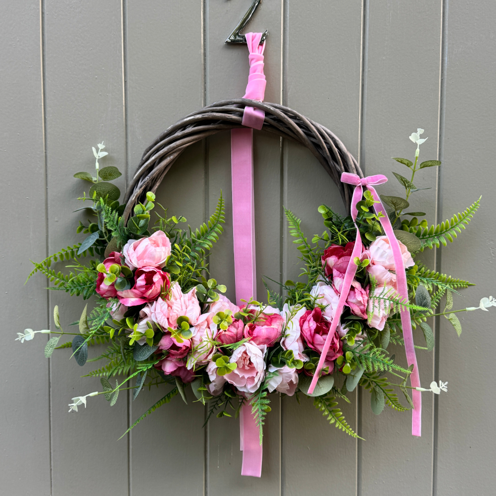 Beautiful wreath of faux flowers on a willow base hangs on a door