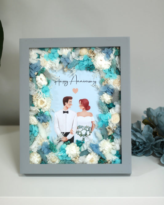 Grey frame with dry turquoise and white flowers with a card "Happy Anniversary"