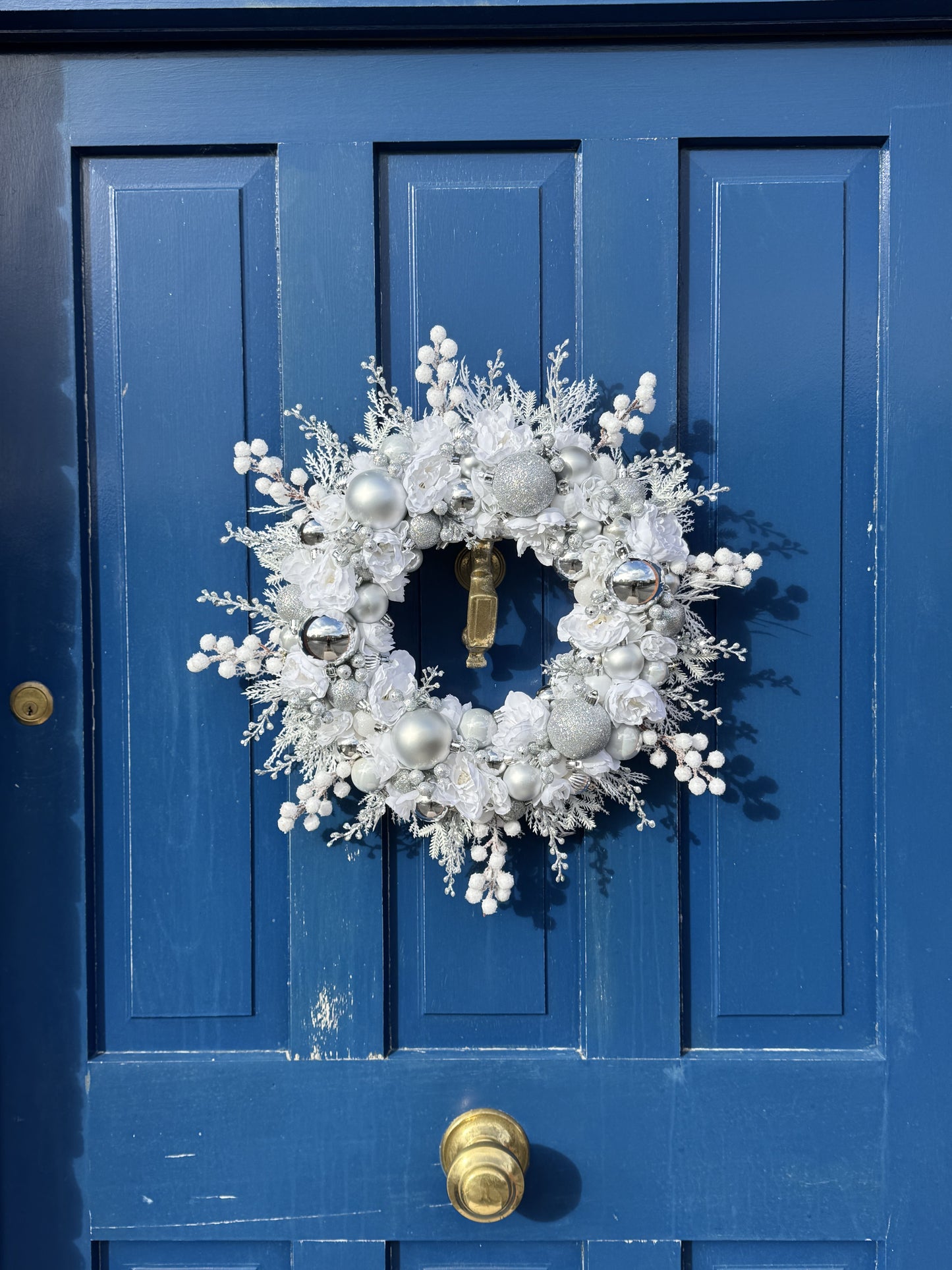 Decorative wreath on a blue door with gold door handles