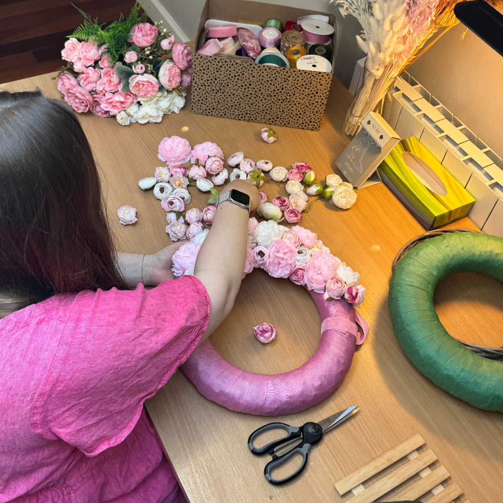 Woman makes a pink floral wreath from faux flowers