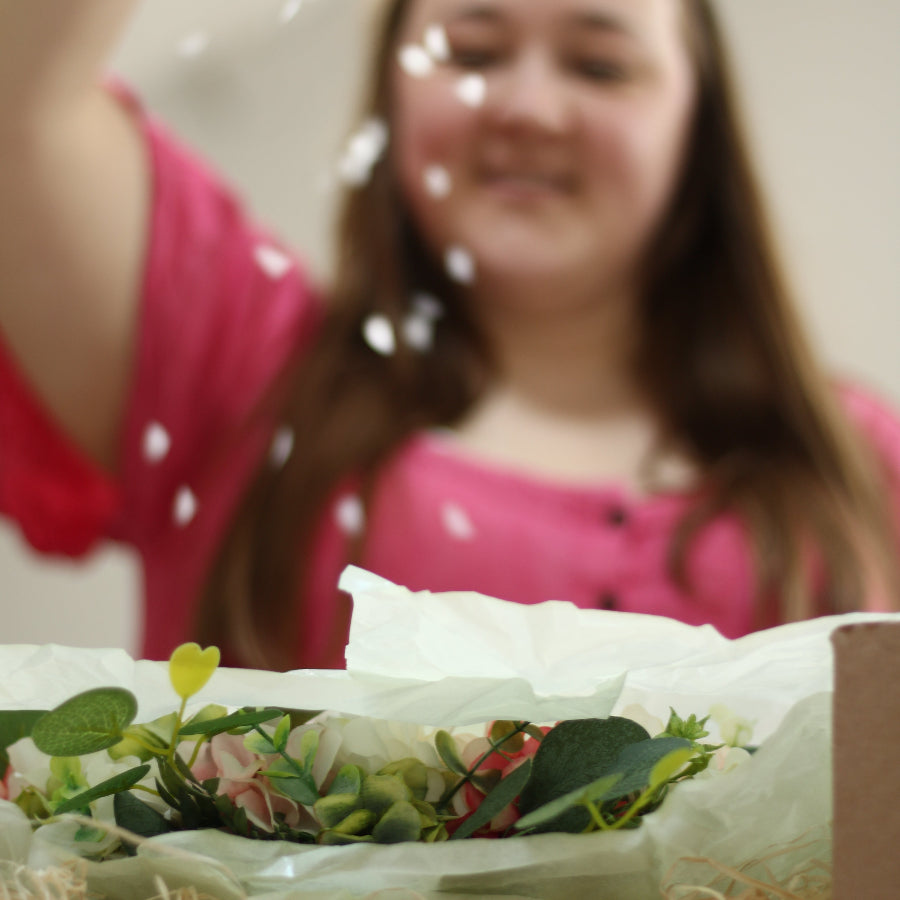Woman sprinkles decorum on a gift packaging of a floral wreath