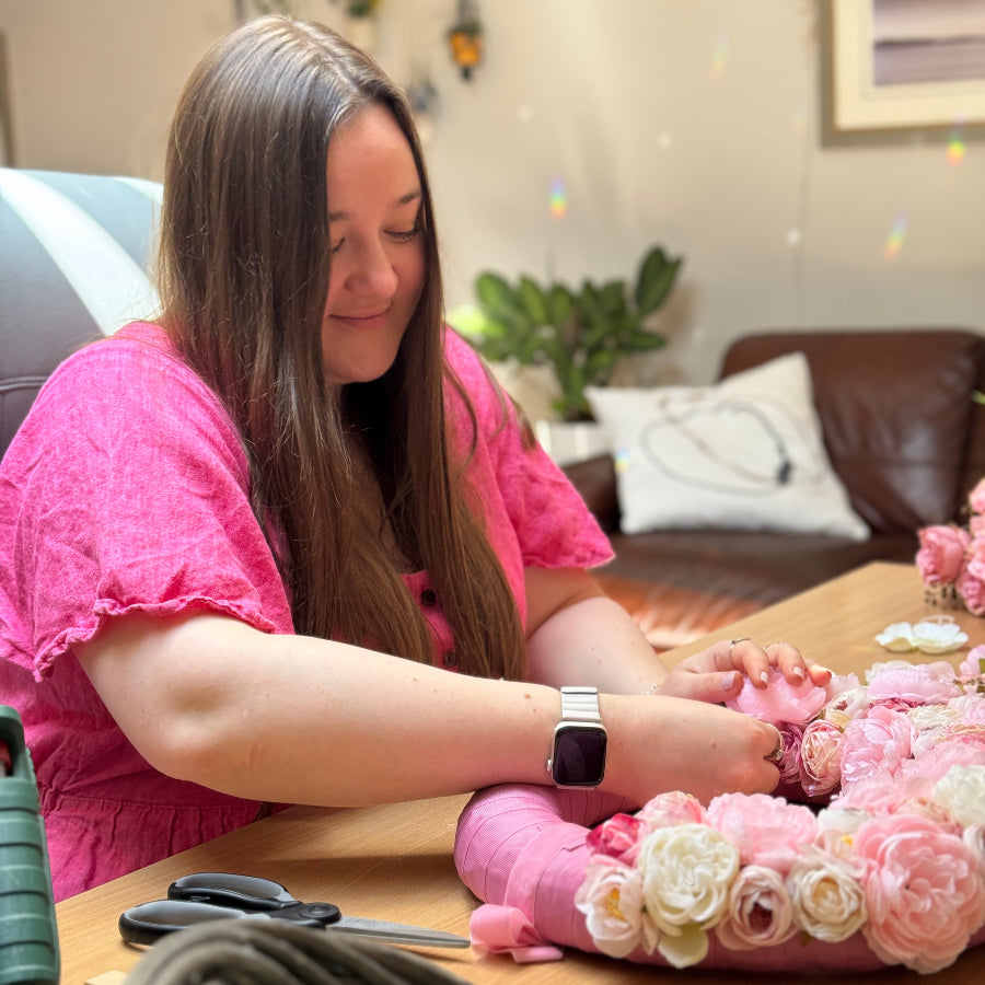 Woman smiles while making an artificial floral wreath